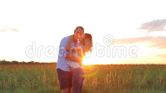美丽的恋爱中的年轻夫妇在夕阳下的田野里旋转视频的预览图