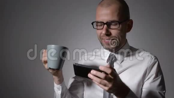 优雅的商人穿着白色衬衫手里拿着一杯咖啡或茶这个人在工作中休息了一下用的是视频的预览图