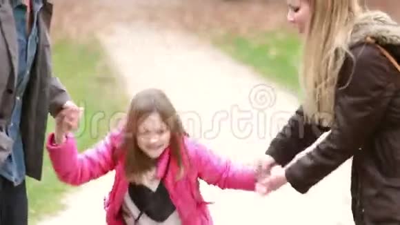 可爱的小女孩和父母牵手跳跃视频的预览图