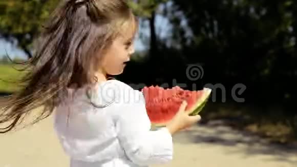 快乐开朗的小女孩穿着白色连衣裙在海滩上玩得开心吃西瓜视频的预览图