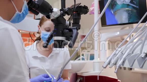 专业医生和女性助理在医院工作时使用光学显微镜视频的预览图