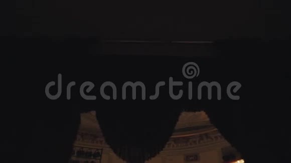 昂贵的金色吊灯出现在音乐厅黑暗窗帘后面视频的预览图