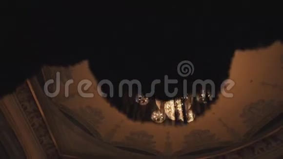 豪华的金色吊灯消失在音乐厅的深色窗帘后面视频的预览图
