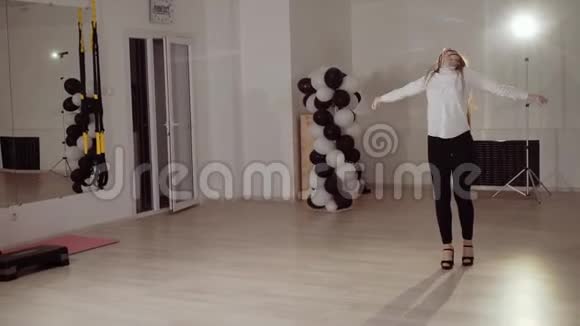 一个穿着白色上衣的女孩在工作室里排练舞蹈视频的预览图