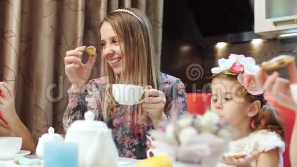 快乐的母亲和女儿正在厨房里喝带饼干的茶视频的预览图