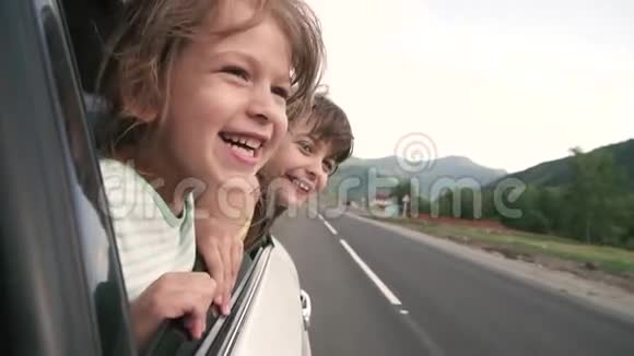 无忧无虑的孩子们探出车窗微笑着两个小女孩在车里玩得很开心慢动作视频的预览图