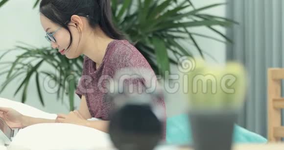 亚洲女人在床上用她的笔记本电脑浏览网页视频的预览图