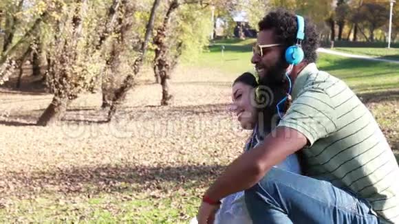 一个男人抱着女孩在公园里用耳机听音乐视频的预览图