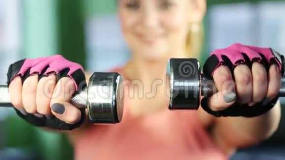 年轻快乐的微笑女人穿着运动服用哑铃做健身运动视频的预览图