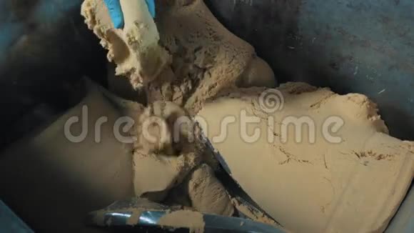 男性手戴蓝色手套将一块动力砂放入磨床视频的预览图