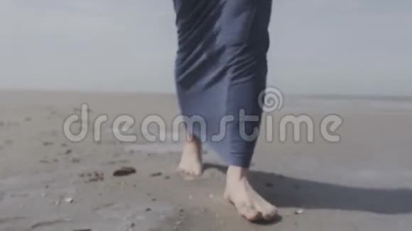 穿着牛仔夹克在孤独的海滩上散步的性感年轻女人视频的预览图
