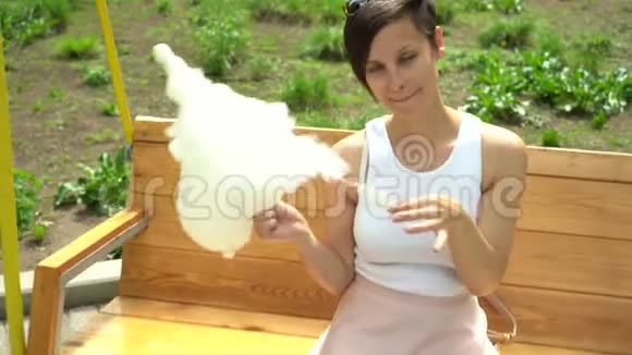 一个微笑兴奋的女孩在游乐园拿棉花糖的肖像视频的预览图