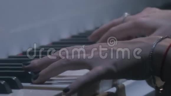 女音乐家手臂推着白色钢琴琴键晚上音乐厅视频的预览图