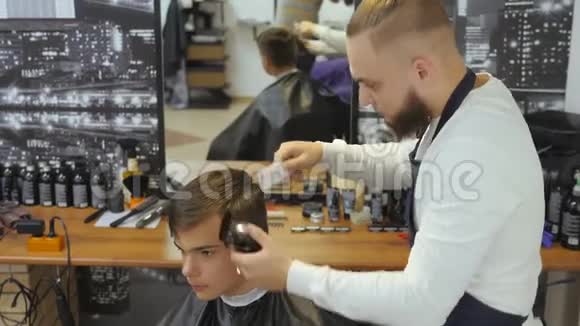 男士美容师理发店一个年轻人从一个留着胡子的男人那里得到理发和理发服务视频的预览图