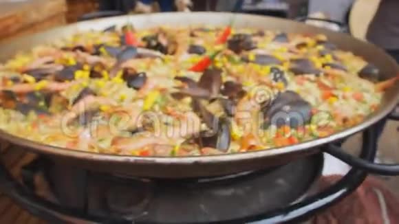 西班牙海鲜饭和黄米饭虾和贻贝在食品市场上烹饪放大摄像机街头美食节视频的预览图