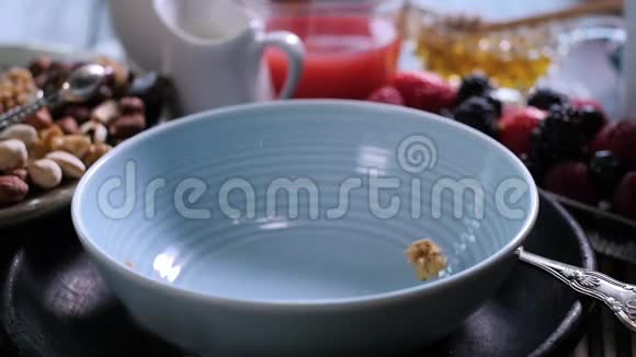 早餐谷类食物落在一个有浆果和干水果的碗上慢动作视频的预览图