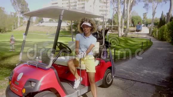 漂亮的女高尔夫球手在红色高尔夫球车上摆姿势视频的预览图