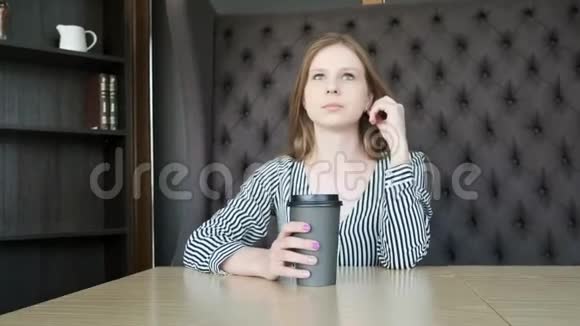 一个年轻漂亮的女孩在一家时尚的咖啡馆里早上下班前喝咖啡在窗户对面他喝酒了视频的预览图