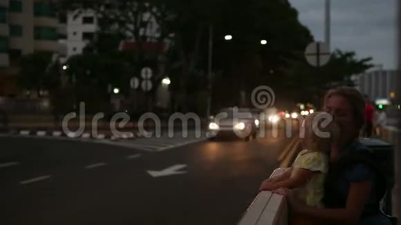 女儿和母亲坐在靠近城市道路的长凳上视频的预览图