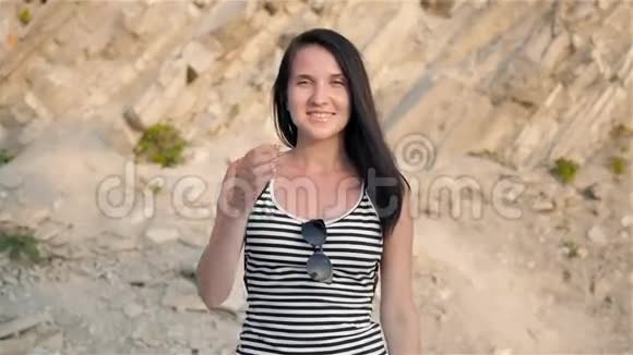 背景中带悬崖的年轻不伦特微笑女人的时尚画像视频的预览图