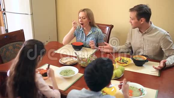 一家人在家里的餐厅用餐青少年双胞胎及其父母视频的预览图