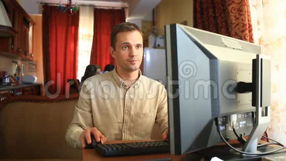 丈夫坐在社交网络中的电脑前而妻子和孩子则在厨房里忙碌丈夫有视频的预览图