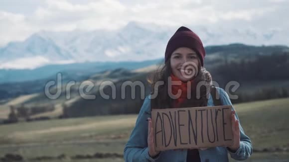在山路上举着冒险标志的少女微笑与欢笑视频的预览图