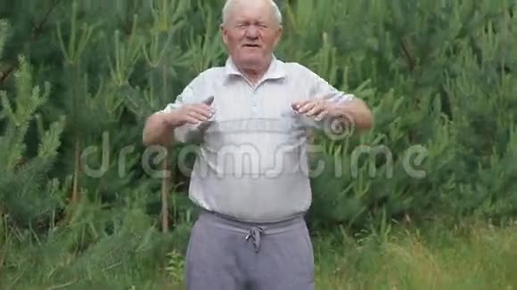 老人做早操在公园里用针叶树伸展双手手指视频的预览图
