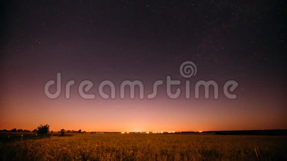 夏田草甸之上的天然夜空闪烁的星星和日落的日出灯光以上的景观视频的预览图