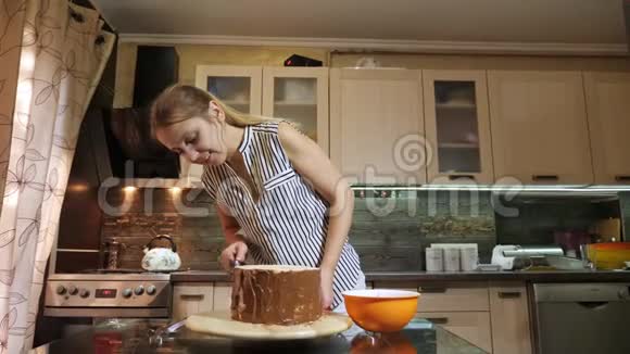 女人用刀子用手把巧克力奶油放在海绵蛋糕上视频的预览图
