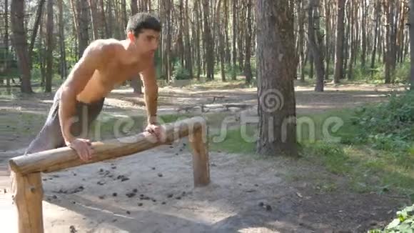 在森林里做俯卧撑的运动员强壮的年轻肌肉男夏季在森林户外训练视频的预览图