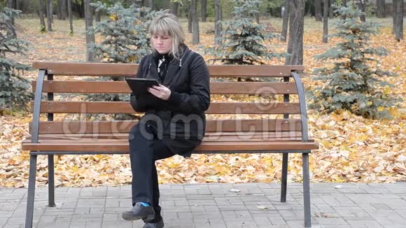 一个拿着平板电脑坐在长凳上的女人视频的预览图