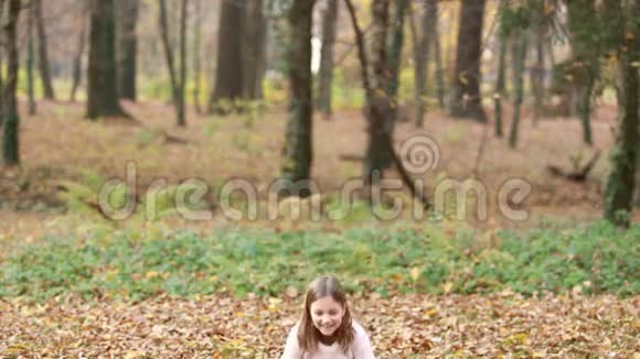 可爱的女孩在公园里扔树叶和跳跃视频的预览图