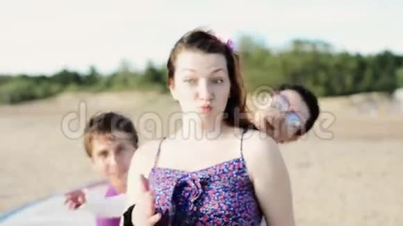两个年轻的女孩和男人在海滩上跳舞镜头微笑晴天假期视频的预览图
