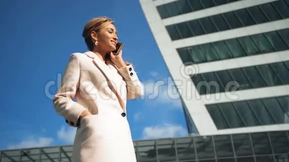 美丽的年轻商务女性在摩天大楼的背景下打电话视频的预览图