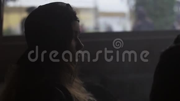 戴帽子的女孩坐在房间里她周围都是蒸汽窗外的人视频的预览图