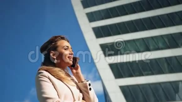 美丽的年轻商务女性在摩天大楼的背景下打电话视频的预览图