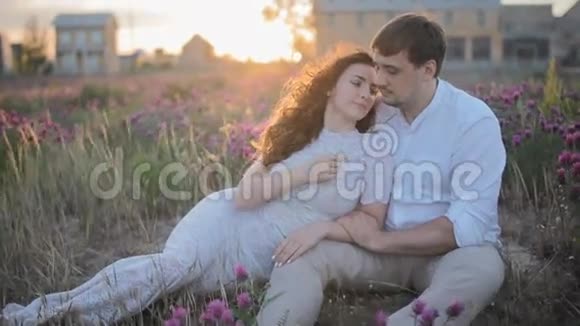 年轻的白种人夫妇坐在田野里视频的预览图