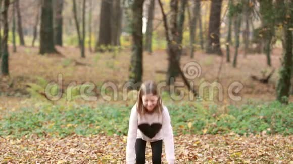 可爱的女孩在公园里扔树叶和跳跃视频的预览图
