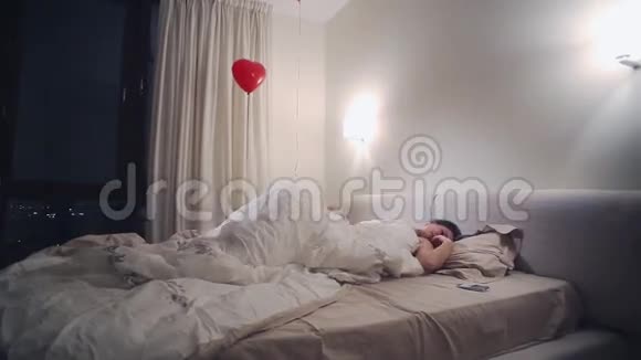 年轻有魅力的女人不能在卧室里睡觉检查智能手机台灯红气球视频的预览图