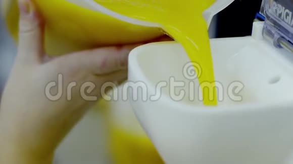 女人的手把黄色的液体倒进机器里视频的预览图