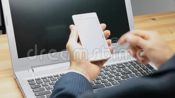 商务人士滑式智能手机或带有笔记本电脑背景的移动电话视频的预览图