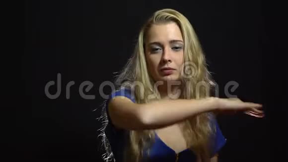 美丽的金发女郎穿着蓝色礼服在黑底工作室跳舞视频的预览图
