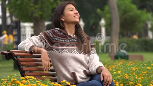 快乐的西班牙裔女性坐在公园里视频的预览图