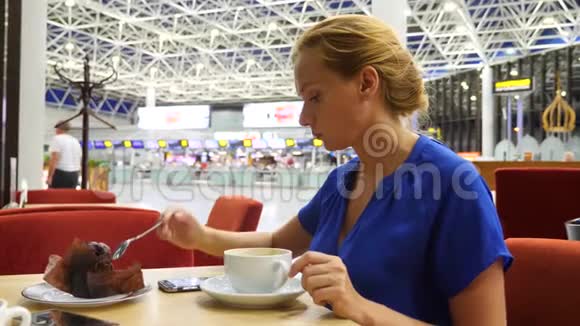 女士在机场候机室使用智能手机她喝咖啡对机场飞行的期望4k慢动作视频的预览图