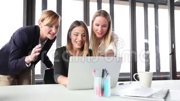 三个美丽的微笑女商人带着笔记本电脑兴高采烈视频的预览图