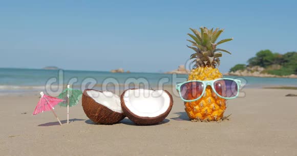 在热带海滩上菠萝在炎热的夏季阳光下戴上太阳镜在热带异国海岸上拍摄一幅水果特写视频的预览图