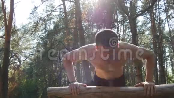 在森林里做俯卧撑的运动员强壮的年轻肌肉男夏季在森林户外训练视频的预览图