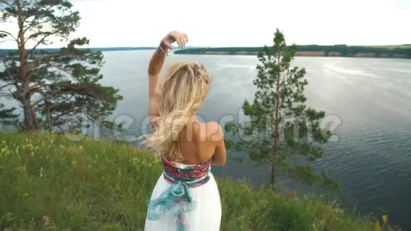 站在河岸岩石上的年轻金发女人视频的预览图
