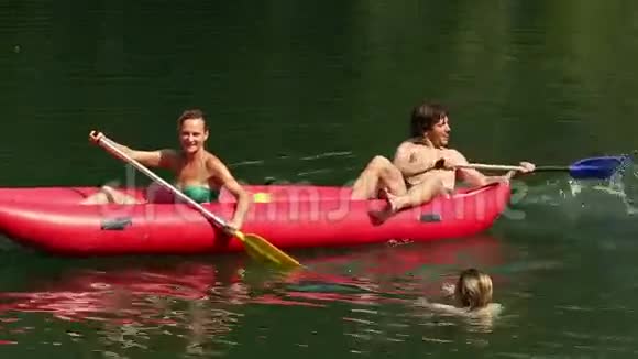 坐在独木舟上的朋友在水中的泼水女孩用桨视频的预览图